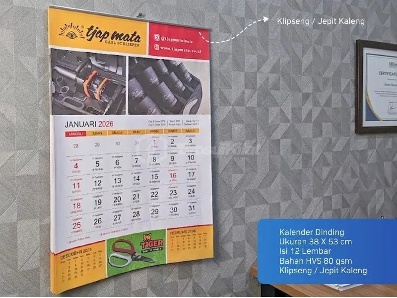 Kalender dinding 12 lembar bahan HVS 80 gsm dijepit klipseng kaleng terpasang di dinding